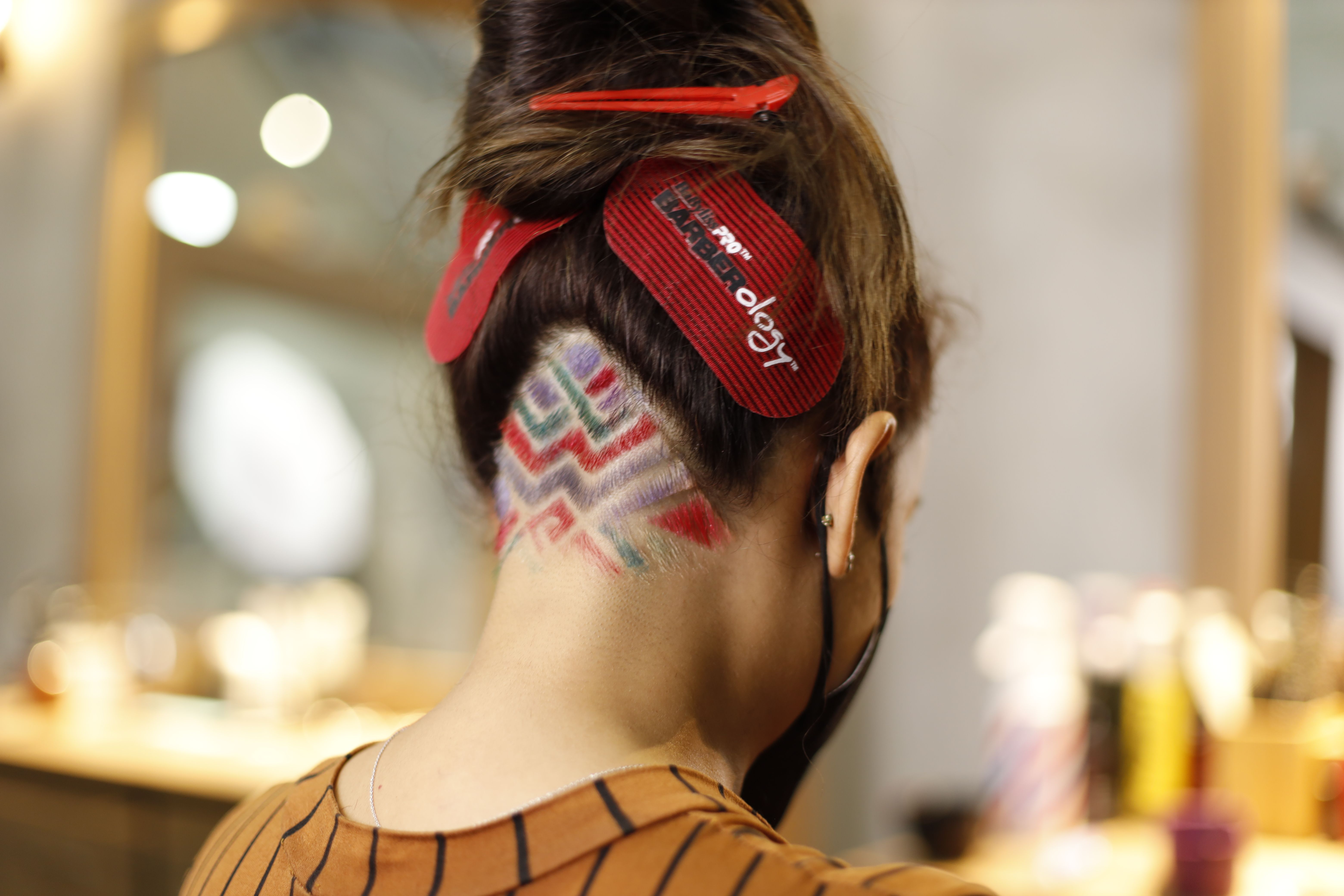 Close-up of a woman's colorful geometric undercut design shaved into the nape of her hair