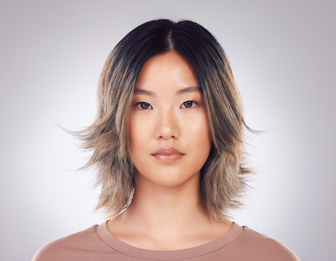 Young woman with a shoulder-length balayage wolf cut, face-framing layers softening her features